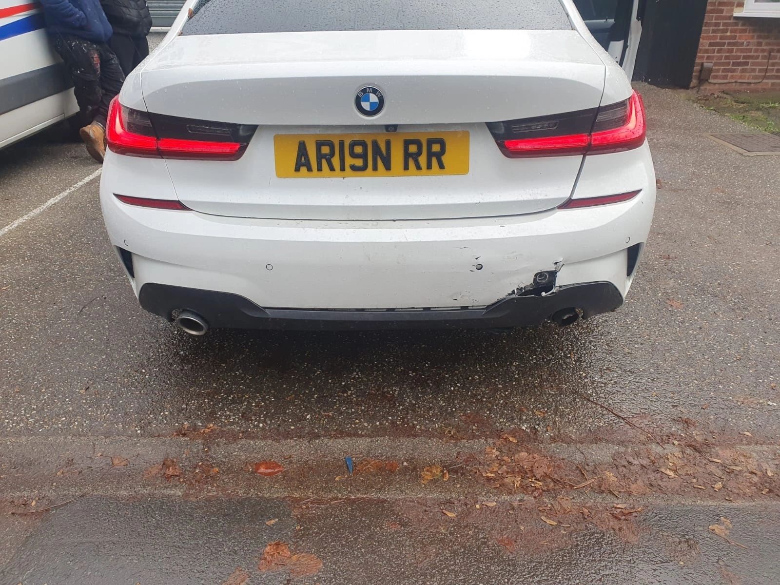 Scuffed and scratched white BMW rear bumper showing kerb damage before repair