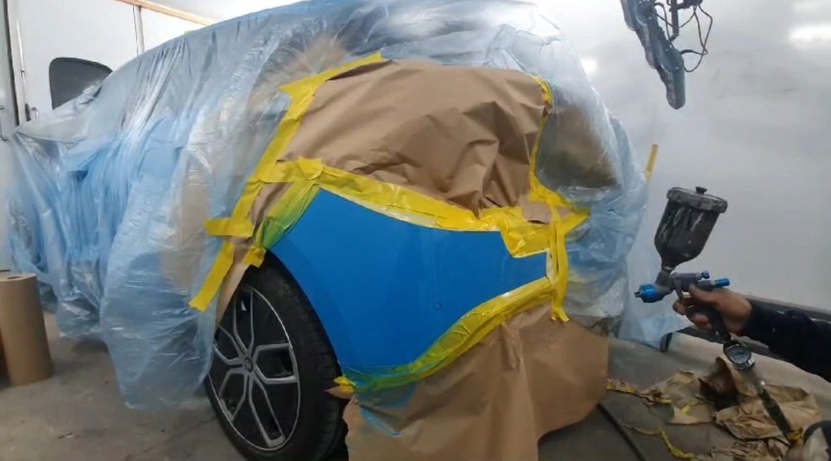 Fresh paint being sprayed onto a car panel during a respray