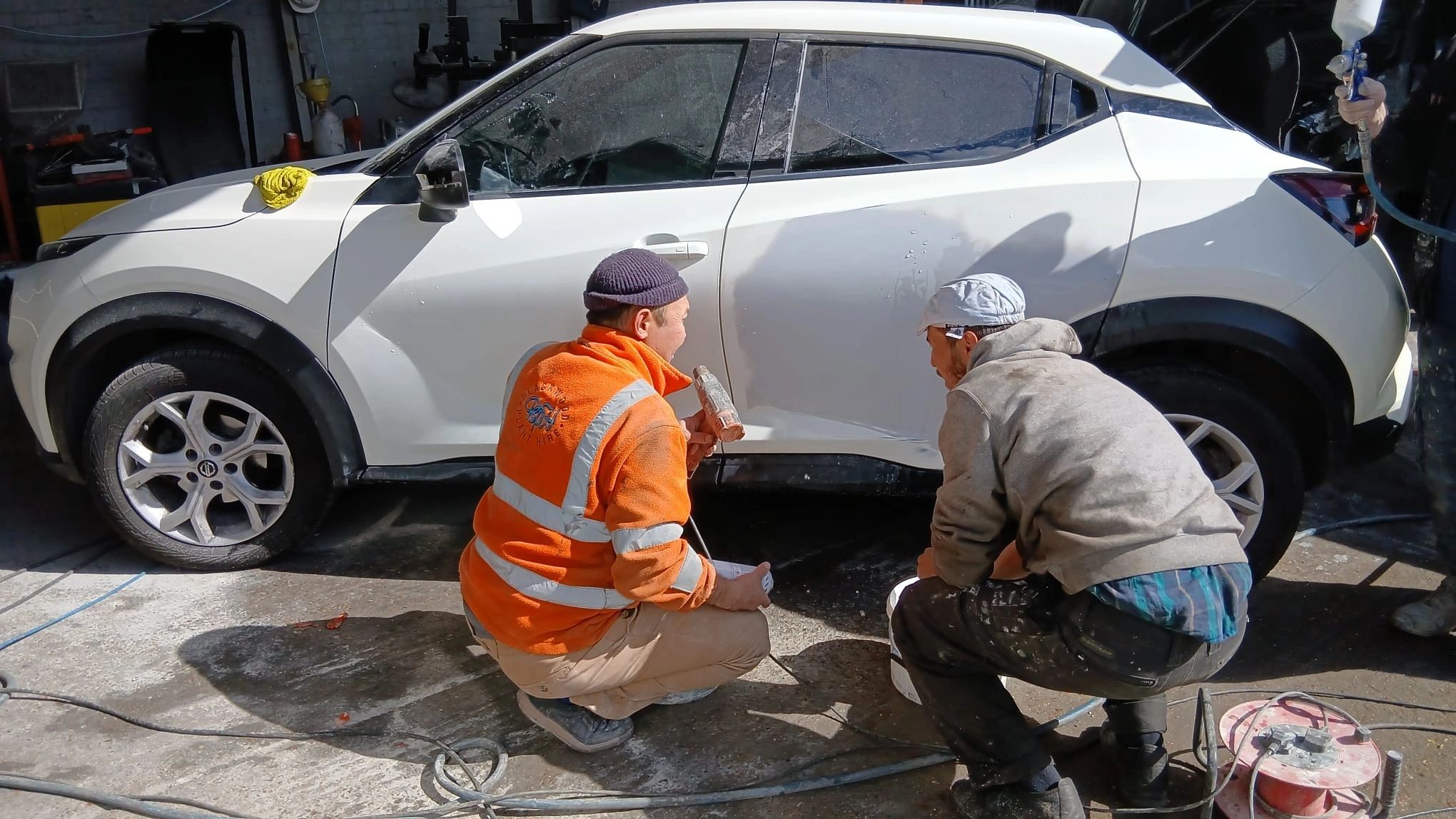 Two of the team inspecting a white car together